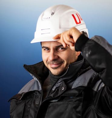 Construction worker wearing a safety helmet, smiling confidently at the camera.